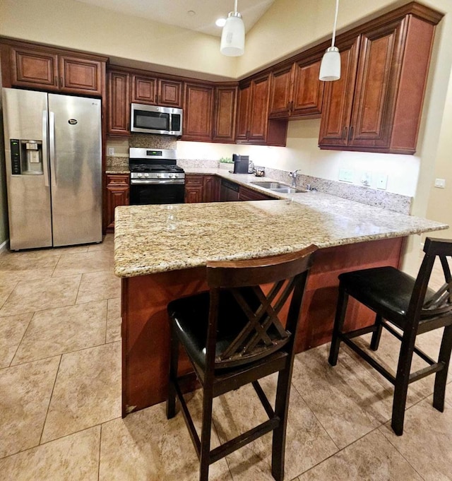 kitchen with kitchen peninsula, a breakfast bar area, stainless steel appliances, decorative light fixtures, and sink