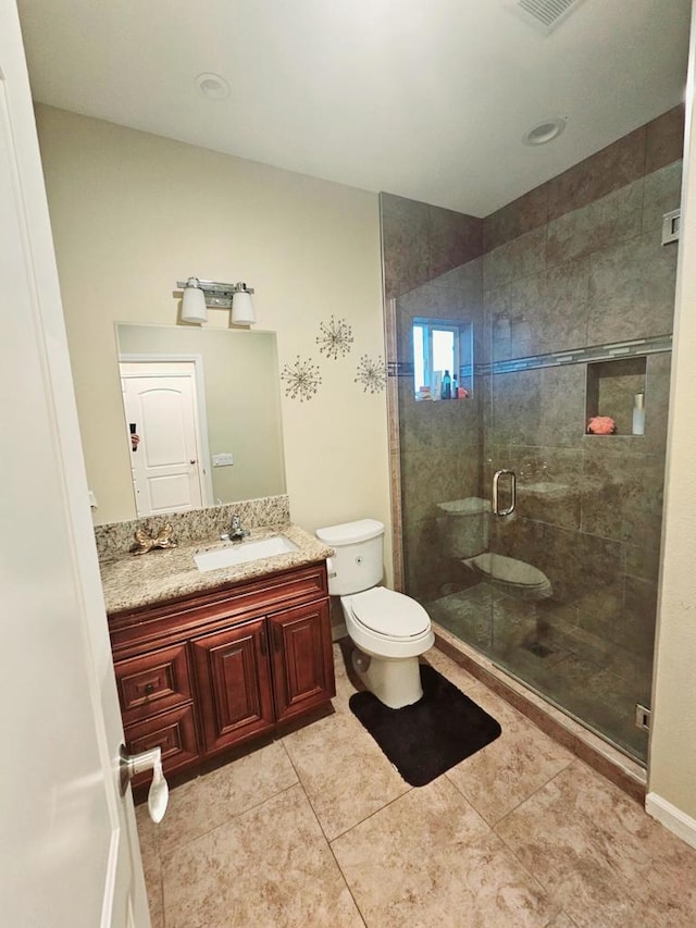 bathroom with a shower with shower door, toilet, vanity, and tile patterned flooring