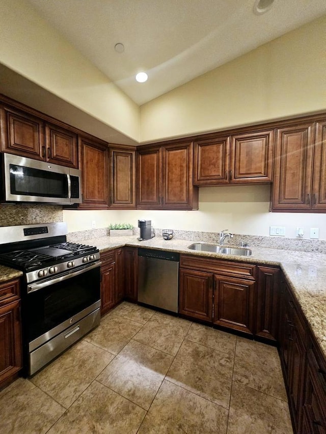 kitchen featuring vaulted ceiling, stainless steel appliances, light stone counters, and sink