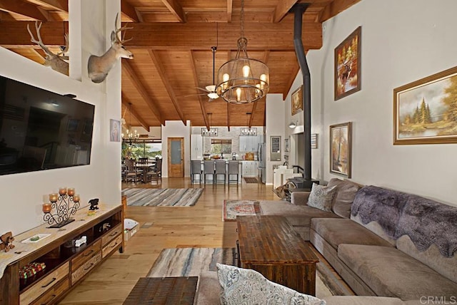 living room with wood ceiling, high vaulted ceiling, a notable chandelier, light hardwood / wood-style floors, and beamed ceiling