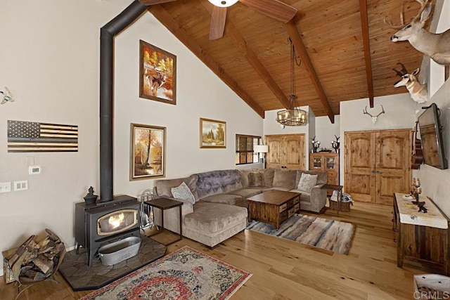 living room with high vaulted ceiling, beamed ceiling, a wood stove, wood ceiling, and light hardwood / wood-style flooring