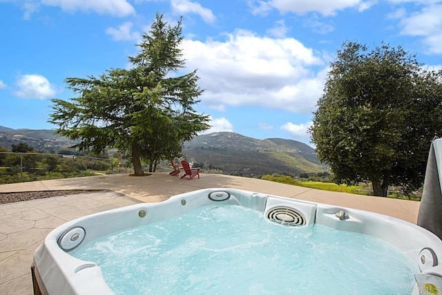 view of swimming pool featuring a mountain view, a patio area, and a hot tub