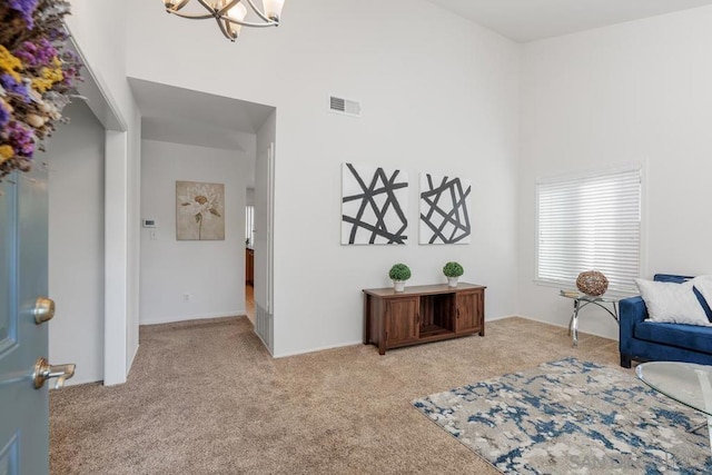 living area featuring a towering ceiling, light colored carpet, and an inviting chandelier