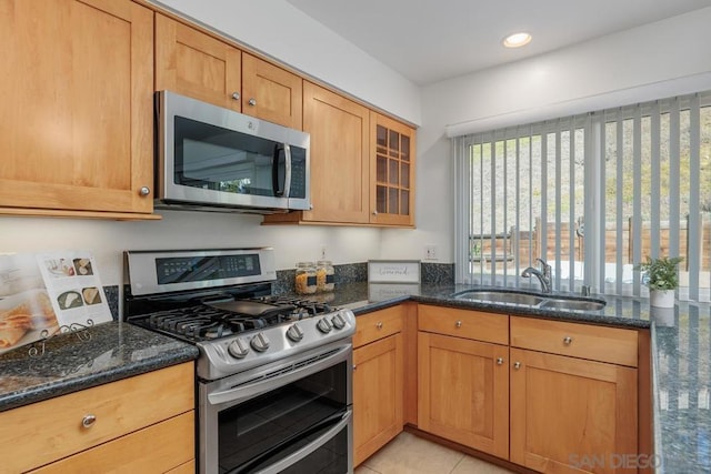 kitchen featuring light tile patterned floors, appliances with stainless steel finishes, sink, and dark stone countertops