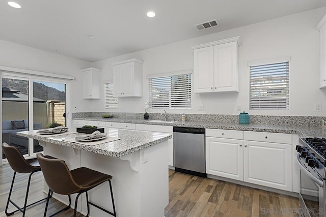 kitchen featuring white cabinets, appliances with stainless steel finishes, a kitchen island, dark wood-type flooring, and sink