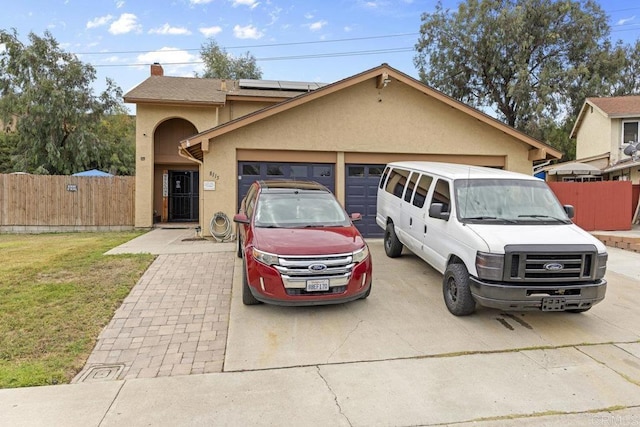 view of front facade featuring a front lawn, solar panels, and a garage