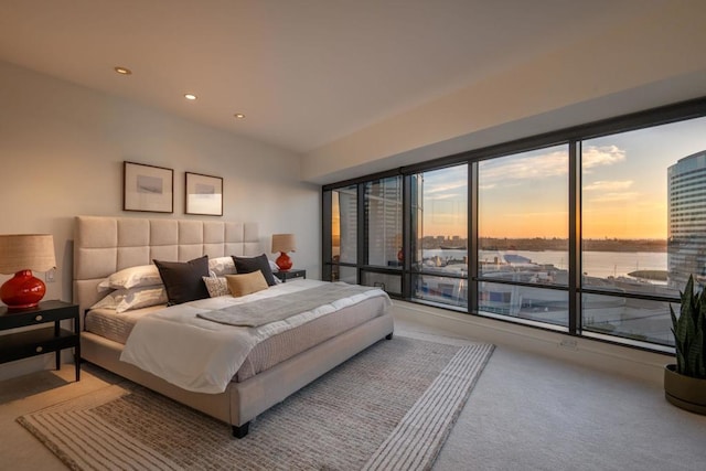 bedroom with a water view and light carpet