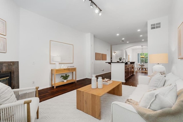 living room with rail lighting, a tile fireplace, and light hardwood / wood-style floors