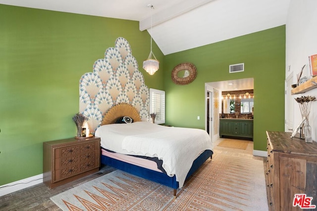 bedroom with beam ceiling, ensuite bathroom, and high vaulted ceiling