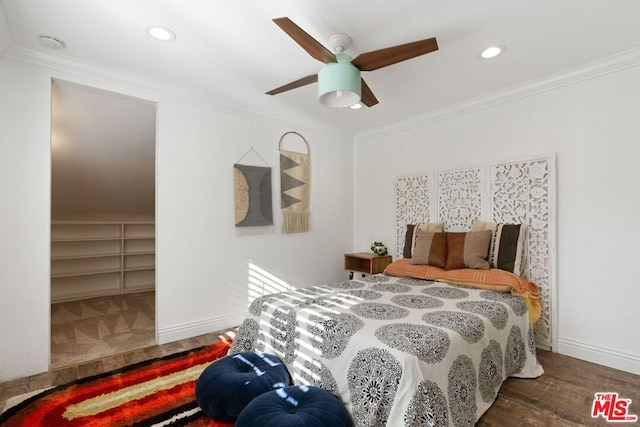 bedroom with ceiling fan, wood-type flooring, crown molding, a spacious closet, and a closet