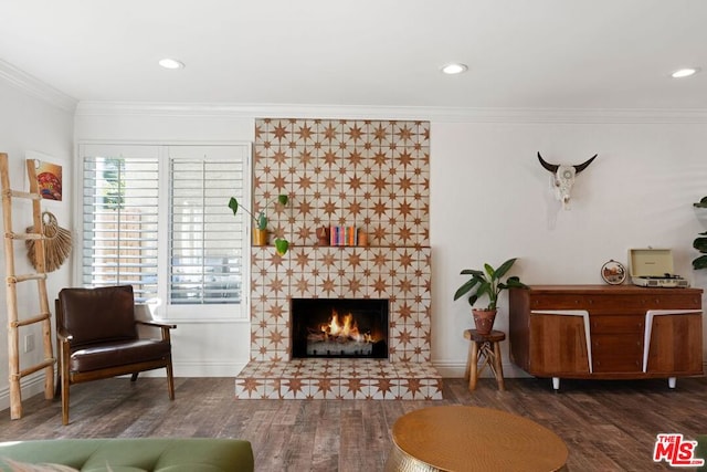 living room featuring a tiled fireplace, dark hardwood / wood-style flooring, and ornamental molding