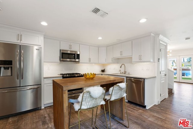 kitchen with white cabinetry, appliances with stainless steel finishes, and dark hardwood / wood-style flooring