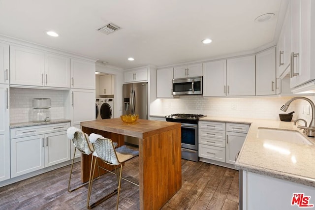 kitchen with washer and clothes dryer, sink, white cabinetry, and appliances with stainless steel finishes