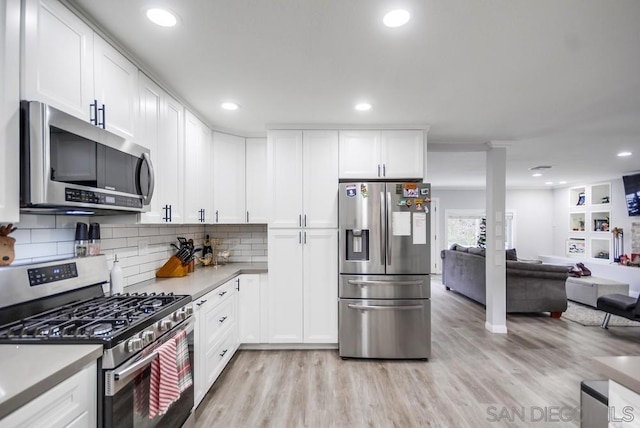 kitchen featuring light wood-type flooring, white cabinets, decorative backsplash, and appliances with stainless steel finishes