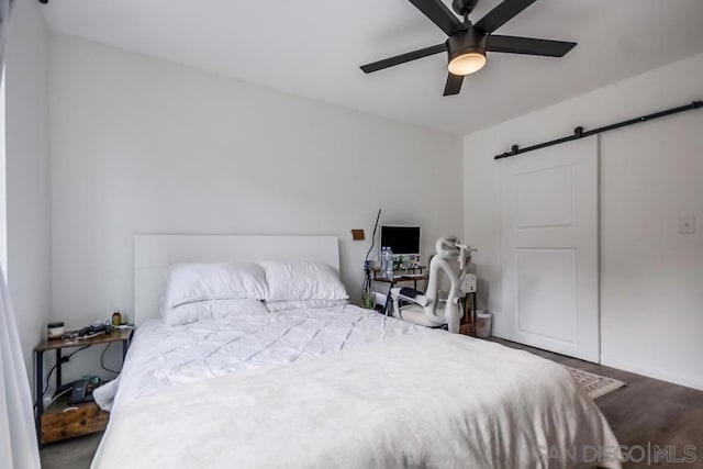 bedroom featuring ceiling fan, hardwood / wood-style flooring, and a barn door