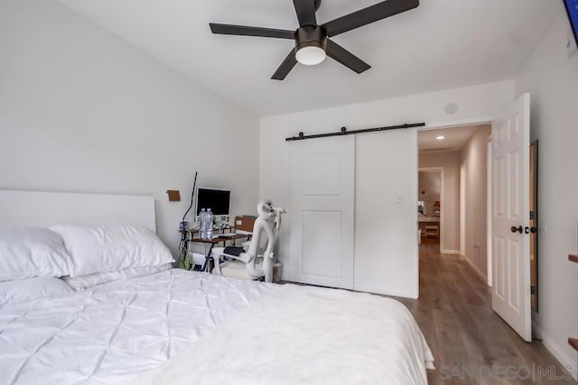 bedroom featuring ceiling fan, wood-type flooring, and a barn door