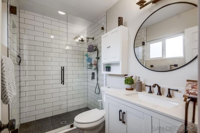 bathroom with toilet, vanity, and a shower with door