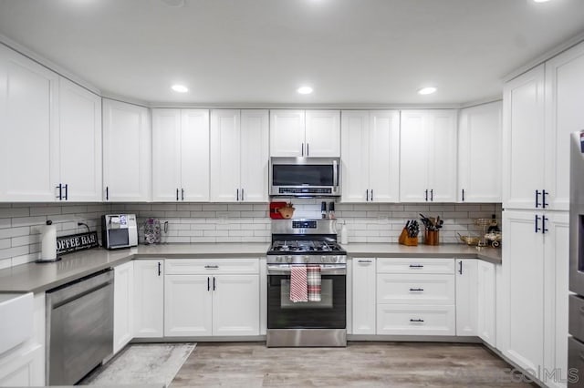 kitchen featuring appliances with stainless steel finishes, light hardwood / wood-style floors, white cabinetry, and tasteful backsplash