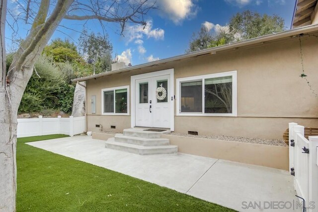 entrance to property featuring a yard and a patio