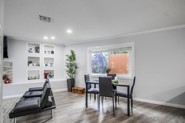 dining room featuring hardwood / wood-style flooring, built in shelves, and ornamental molding