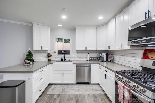 kitchen with decorative backsplash, sink, light wood-type flooring, appliances with stainless steel finishes, and white cabinets