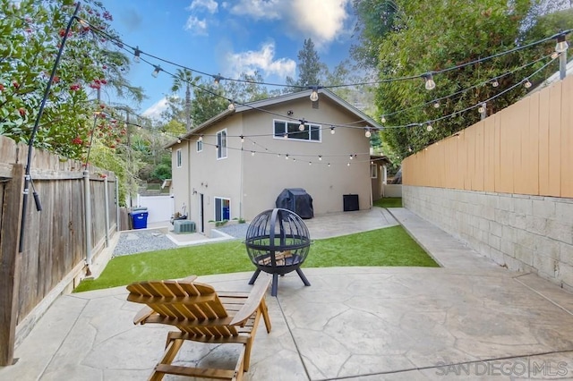 rear view of property featuring a patio area, an outdoor fire pit, central AC unit, and a lawn