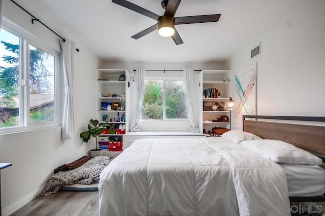 bedroom featuring ceiling fan, wood-type flooring, and multiple windows