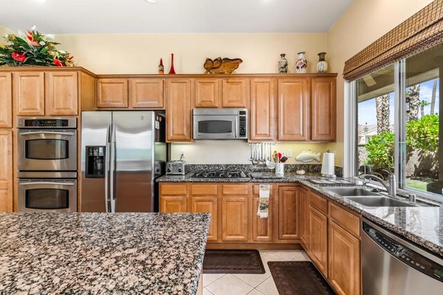 kitchen featuring light tile patterned floors, sink, appliances with stainless steel finishes, and dark stone counters