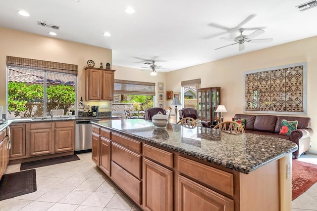 kitchen featuring light tile patterned flooring, dishwasher, dark stone counters, and a center island