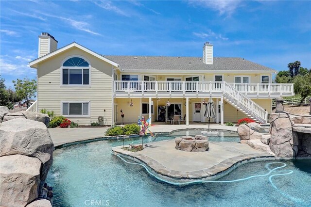 back of house with a patio area, a swimming pool side deck, a fire pit, and pool water feature