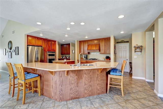 kitchen featuring a spacious island, stainless steel appliances, sink, a kitchen breakfast bar, and premium range hood