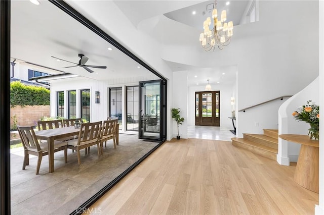 foyer featuring a healthy amount of sunlight, french doors, ceiling fan with notable chandelier, and light hardwood / wood-style floors