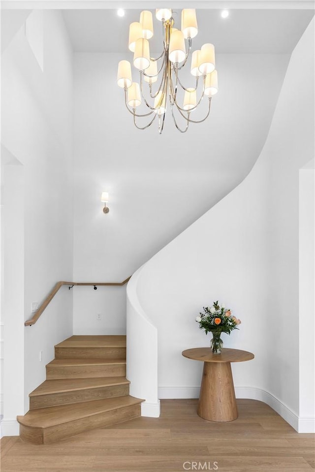 stairway featuring wood-type flooring and an inviting chandelier