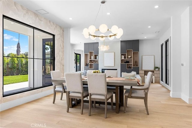 dining area featuring an inviting chandelier, light hardwood / wood-style flooring, and built in shelves