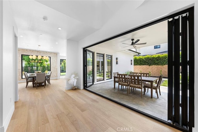 interior space featuring ceiling fan with notable chandelier and light hardwood / wood-style floors