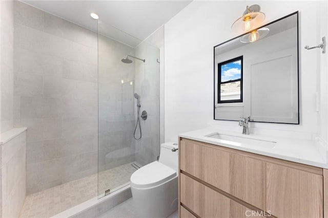 bathroom with toilet, vanity, and tiled shower