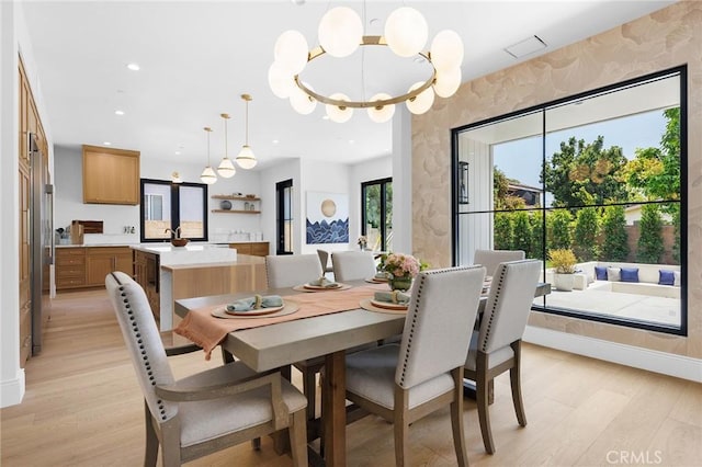 dining room with sink, light hardwood / wood-style flooring, and a chandelier