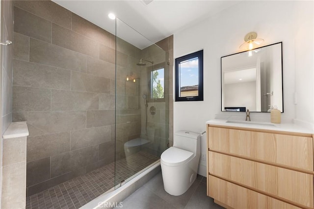 bathroom featuring toilet, vanity, a tile shower, and tile patterned flooring