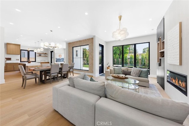 living room with an inviting chandelier, a fireplace, and light hardwood / wood-style flooring