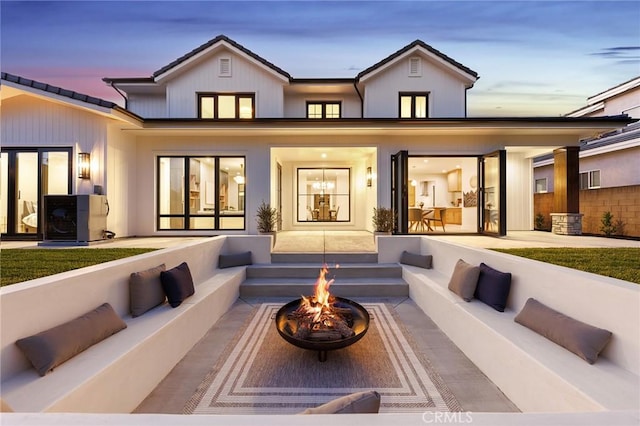 back house at dusk with a patio area and a fire pit