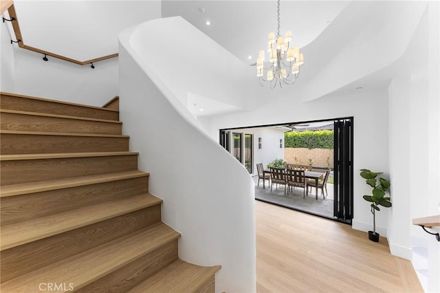 stairs with a notable chandelier, a towering ceiling, and hardwood / wood-style floors