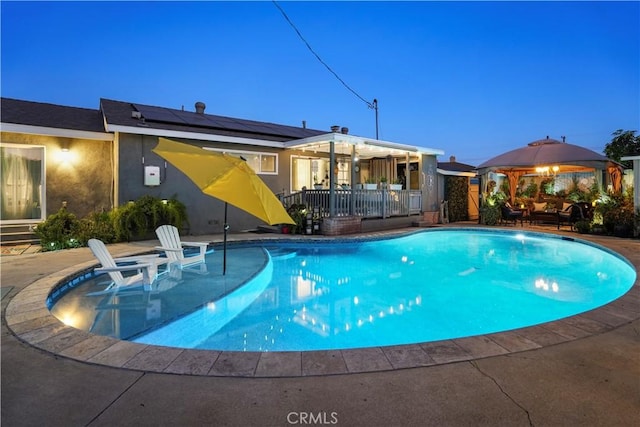 pool at dusk with an outdoor hangout area, a gazebo, and a patio area