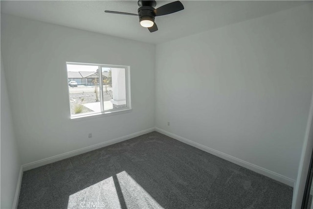 spare room with ceiling fan and dark carpet