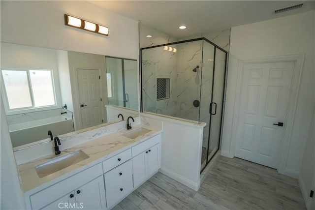 bathroom featuring hardwood / wood-style floors, vanity, and shower with separate bathtub