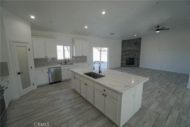 kitchen with a kitchen island with sink, dishwasher, sink, and white cabinetry