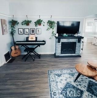 living room featuring dark hardwood / wood-style floors and a stone fireplace