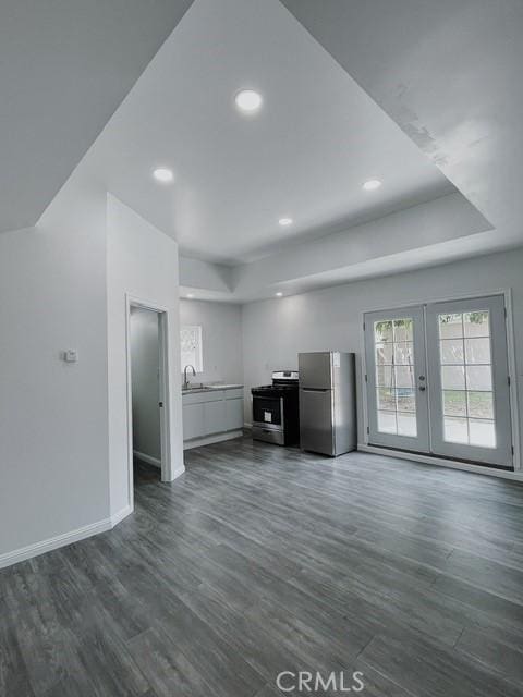 unfurnished living room with sink, dark hardwood / wood-style flooring, and french doors