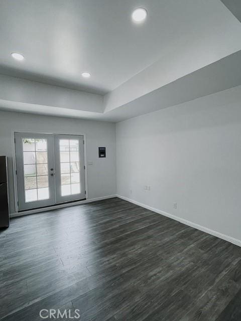 spare room with a tray ceiling, dark hardwood / wood-style floors, and french doors