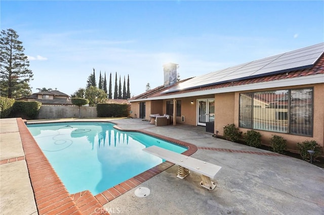 view of swimming pool featuring a patio area and a diving board