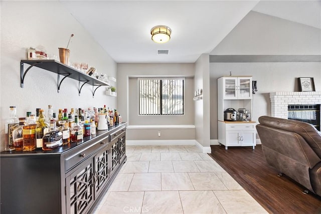 bar featuring a fireplace and light tile patterned flooring